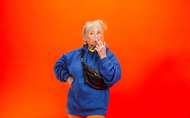 Image showing Senior woman in ultra trendy attire isolated on bright orange background