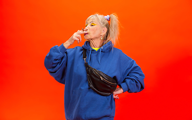 Image showing Senior woman in ultra trendy attire isolated on bright orange background