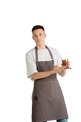 Image showing Isolated portrait of a young male caucasian barista or bartender in brown apron smiling