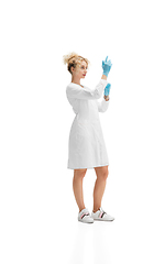 Image showing Portrait of female doctor, nurse or cosmetologist in white uniform and blue gloves over white background