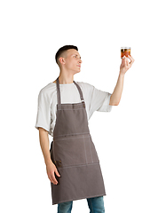 Image showing Isolated portrait of a young male caucasian barista or bartender in brown apron smiling