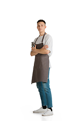 Image showing Isolated portrait of a young male caucasian barista or bartender in brown apron smiling
