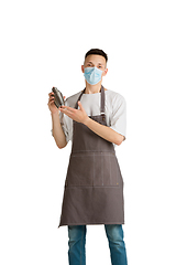 Image showing Isolated portrait of a young male caucasian barista or bartender in brown apron smiling