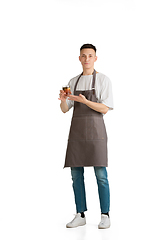 Image showing Isolated portrait of a young male caucasian barista or bartender in brown apron smiling