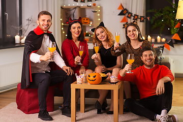 Image showing happy friends in halloween costumes at home party