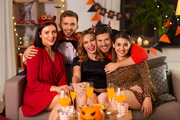 Image showing happy friends in halloween costumes at home party