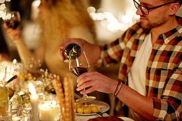 Image showing man pouring red wine into glass at christmas party