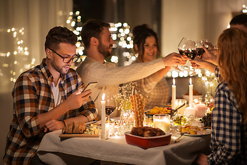Image showing man with smartphone at dinner party with friends