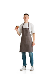 Image showing Isolated portrait of a young male caucasian barista or bartender in brown apron smiling