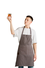 Image showing Isolated portrait of a young male caucasian barista or bartender in brown apron smiling