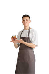 Image showing Isolated portrait of a young male caucasian barista or bartender in brown apron smiling