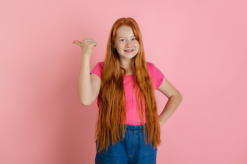 Image showing Caucasian teen girl\'s portrait isolated on coral pink studio background.