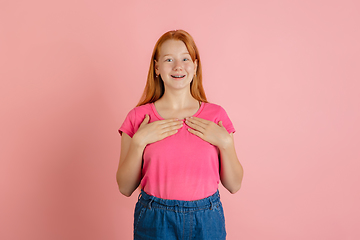 Image showing Caucasian teen girl\'s portrait isolated on coral pink studio background.