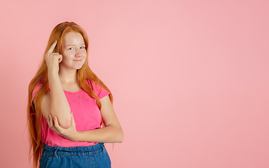 Image showing Caucasian teen girl\'s portrait isolated on coral pink studio background.