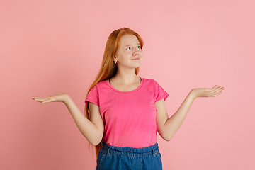 Image showing Caucasian teen girl\'s portrait isolated on coral pink studio background.