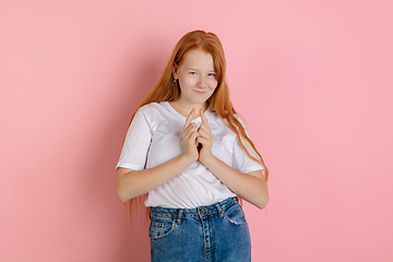 Image showing Caucasian teen girl\'s portrait isolated on coral pink studio background.