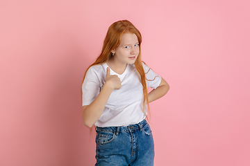 Image showing Caucasian teen girl\'s portrait isolated on coral pink studio background.