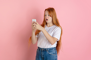 Image showing Caucasian teen girl\'s portrait isolated on coral pink studio background.