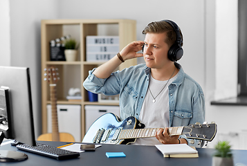 Image showing man in headphones playing bass guitar at home