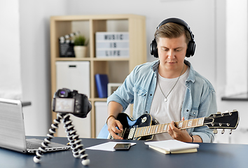 Image showing man or blogger with camera playing guitar at home