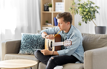 Image showing young man with guitar and music book at home