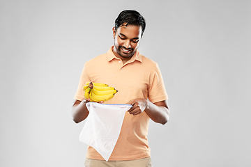 Image showing happy man putting bananas into reusable string bag