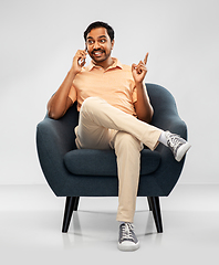 Image showing happy indian man calling on smartphone in chair