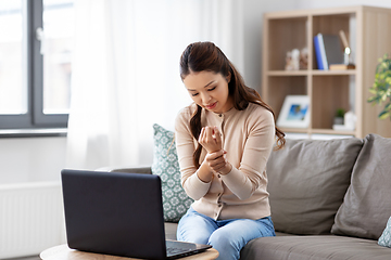 Image showing asian woman with laptop having hand ache at home