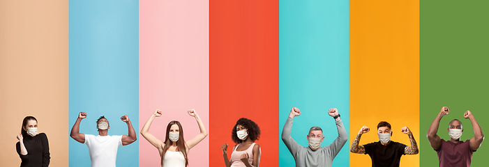 Image showing Young attractive people look astonished on multicolored background, wear funny masks