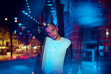 Image showing Cinematic portrait of handsome young man in neon lighted room, stylish musician