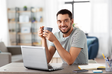 Image showing man with laptop drinking coffee at home office