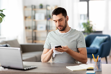 Image showing man cleaning phone with wet wipe at home office