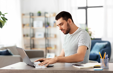 Image showing man cleaning laptop with wet wipe at home office