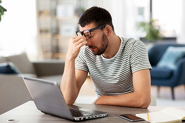 Image showing tired man with laptop working at home office