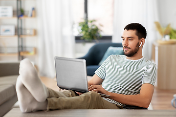 Image showing man with laptop and earphones at home