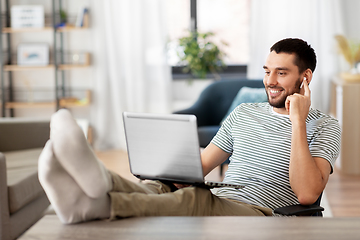 Image showing happy man with laptop and earphones at home