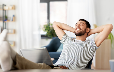 Image showing happy man with laptop resting at home office