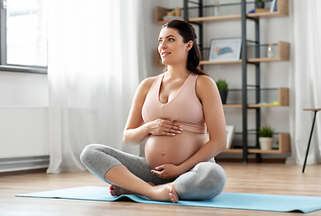 Image showing happy pregnant woman doing yoga at home