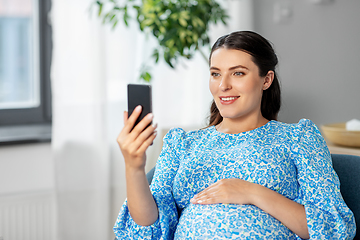 Image showing happy pregnant woman with smartphone at home