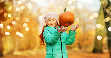 Image showing happy girl playing with pumpkin at autumn park