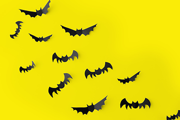 Image showing flock of black paper bats over yellow background