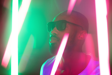 Image showing Cinematic portrait of handsome young man in neon lighted room, stylish musician