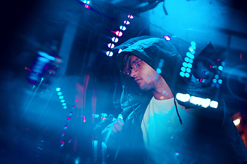 Image showing Cinematic portrait of handsome young man in neon lighted room, stylish musician