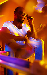 Image showing Cinematic portrait of handsome young man in neon lighted room, stylish musician