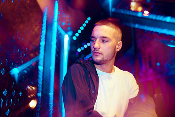 Image showing Cinematic portrait of handsome young man in neon lighted room, stylish musician