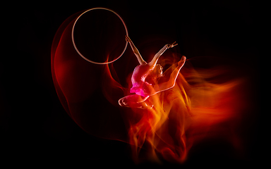 Image showing Young flexible female gymnast isolated on black studio background in mixed light,