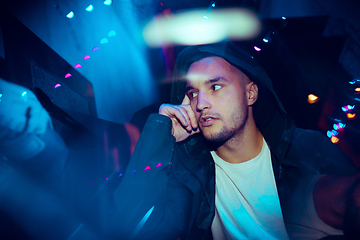 Image showing Cinematic portrait of handsome young man in neon lighted room, stylish musician