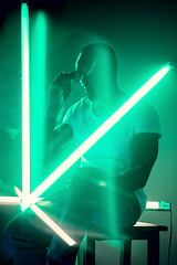 Image showing Cinematic portrait of handsome young man in neon lighted room, stylish musician