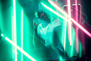 Image showing Cinematic portrait of handsome young man in neon lighted room, stylish musician