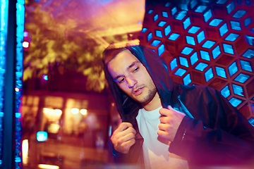 Image showing Cinematic portrait of handsome young man in neon lighted room, stylish musician